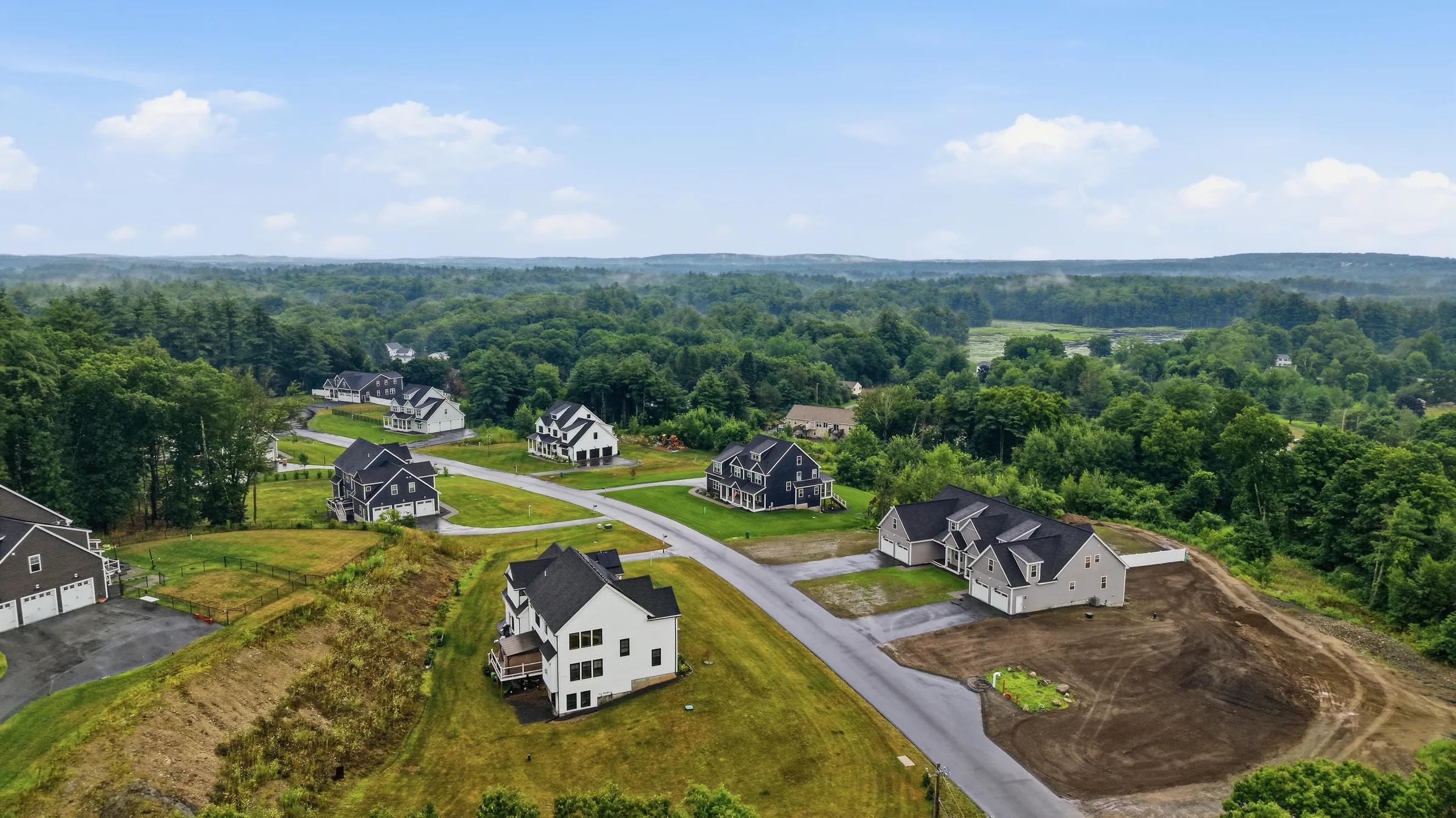 Construction drone photo of a development with finished and in-progress homes on graded lots in Pelham, NH
