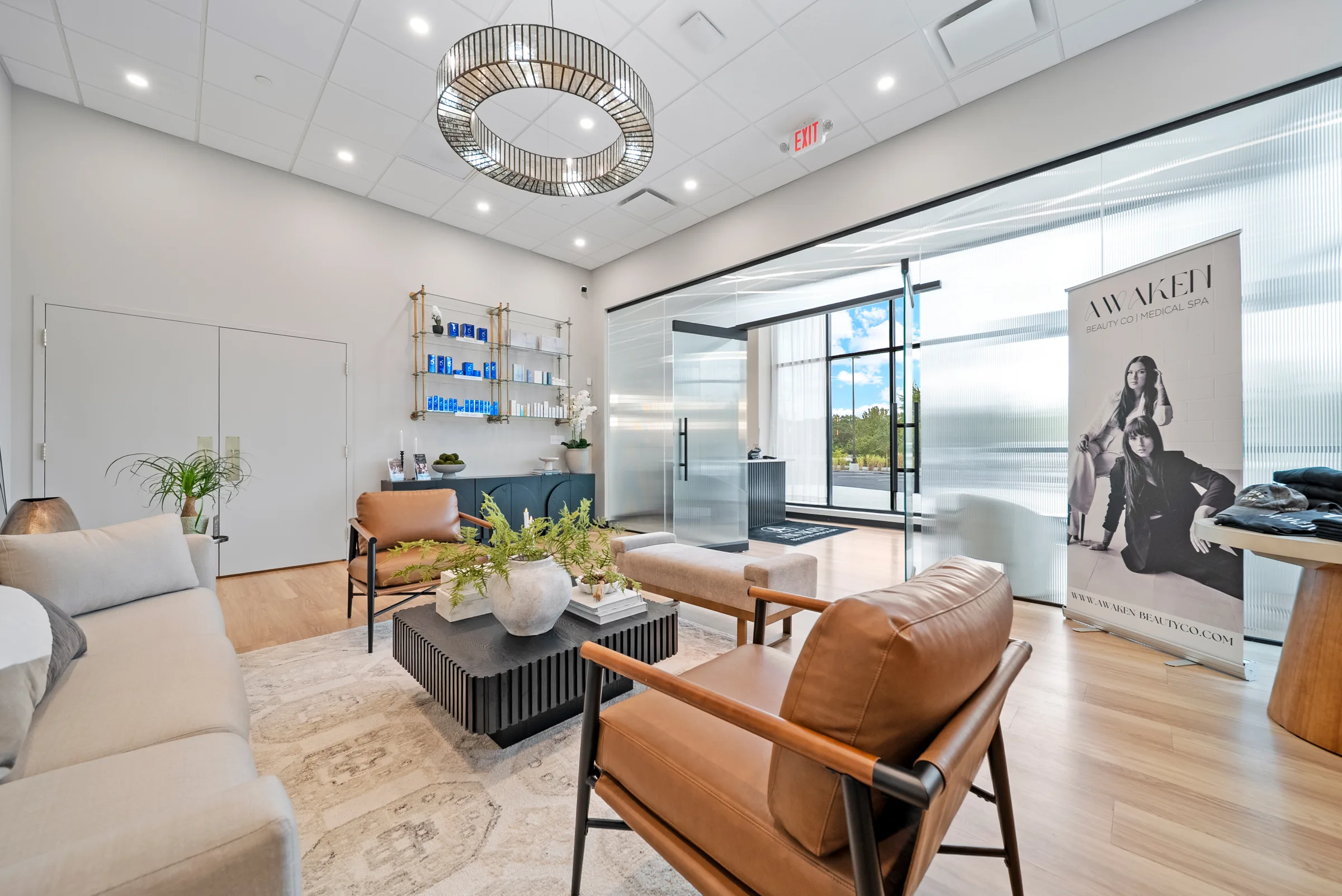 A bright waiting lounge with leather chairs, a lit product shelf, and a glass wall onto the lot
