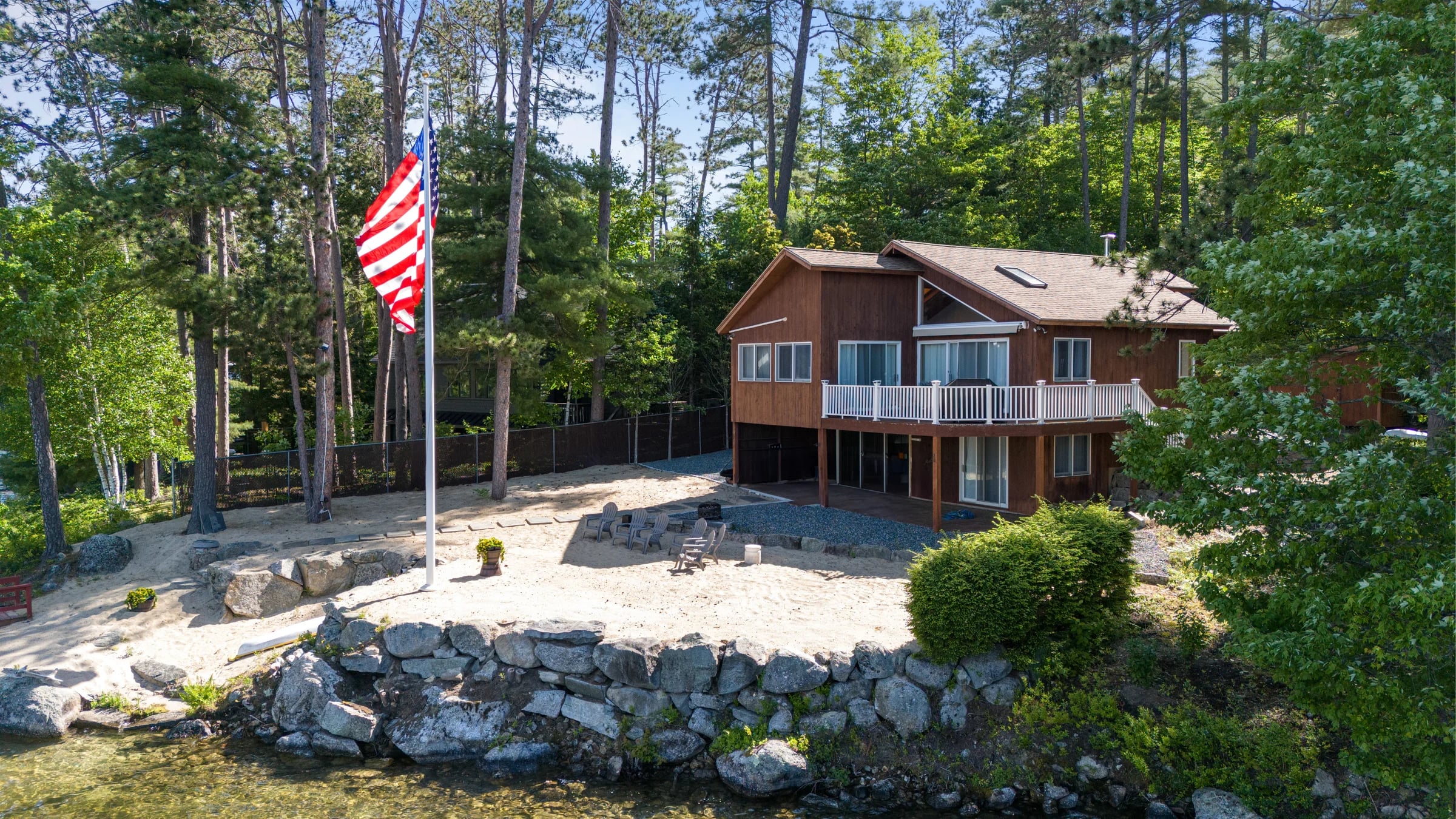 A lakeside home on its wooded waterfront grounds, seen from the water