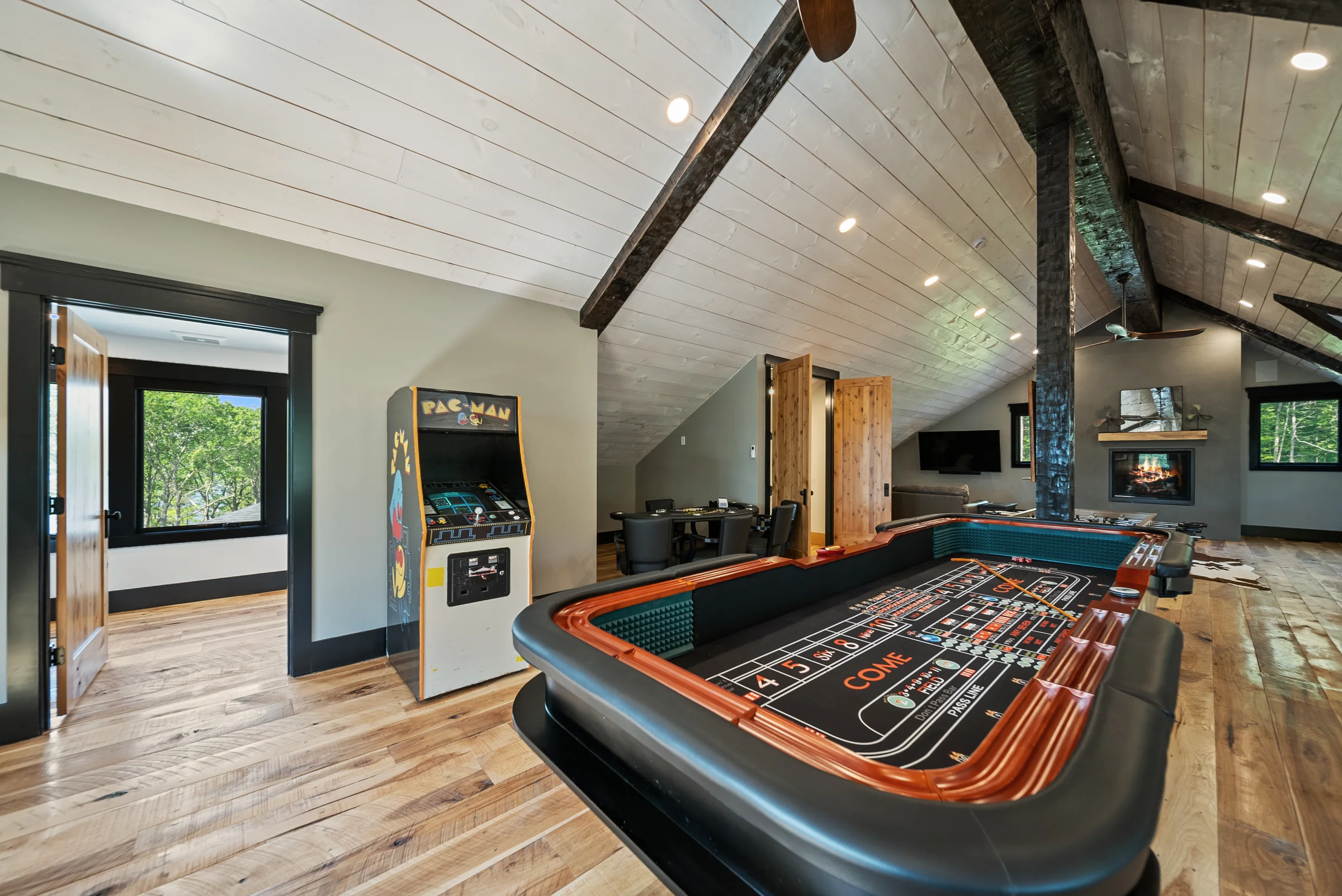 Game room with a casino-style table and arcade machines under a vaulted wood ceiling